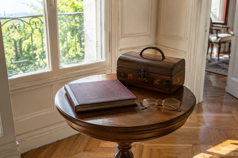 Album photo et boîte à couture posés sur un guéridon avant le tri