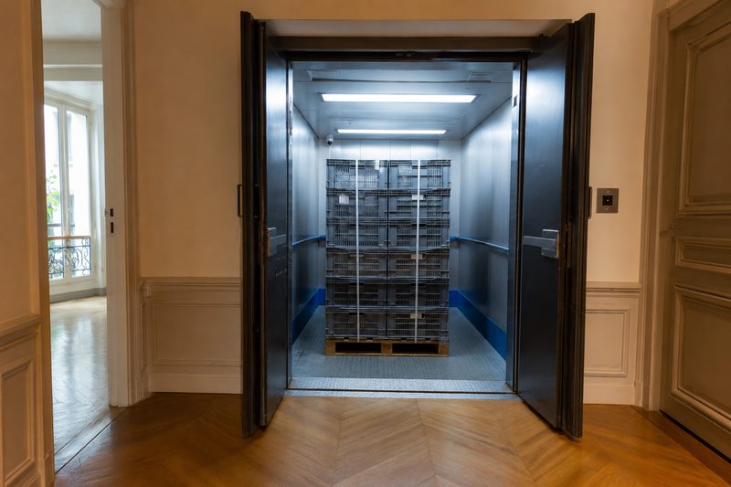 Caisses navettes prêtes au départ devant un monte-charge d’immeuble de bureaux