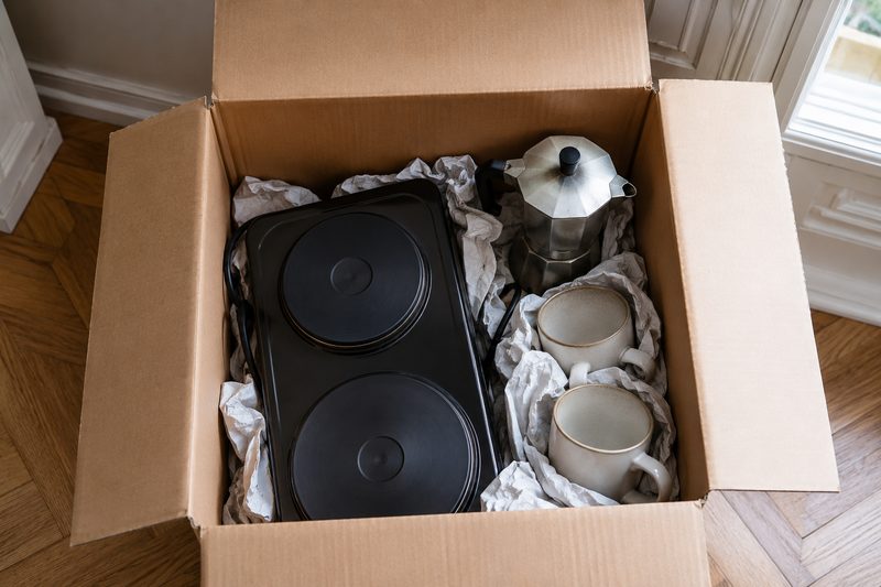 Petit électroménager calé dans un carton pour un déménagement de studio