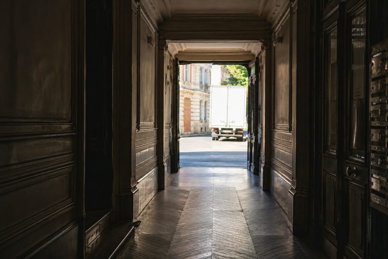 Porte cochère ouverte sur la rue et le camion, dans un immeuble ancien de Bois-Colombes